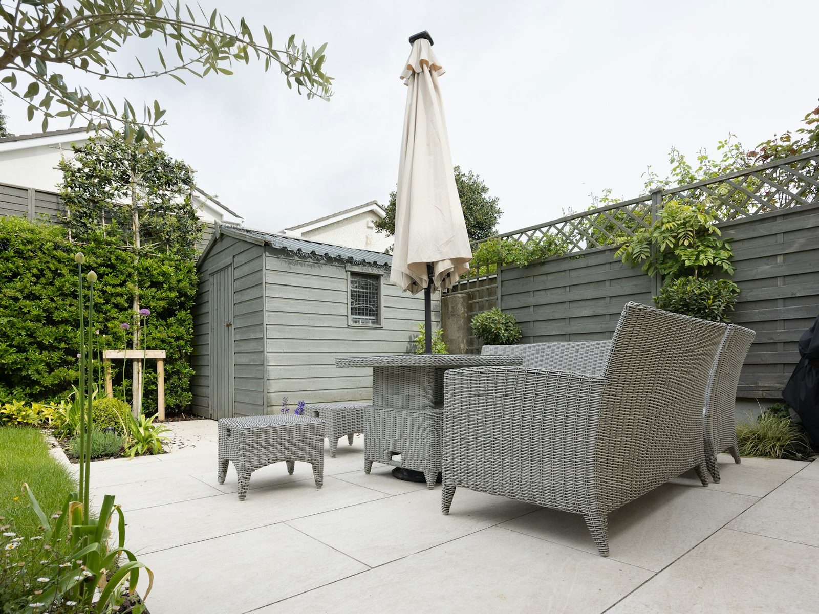 Terrasse aus großen Platten mit Lounge, Gartenhaus und Sichtschutz